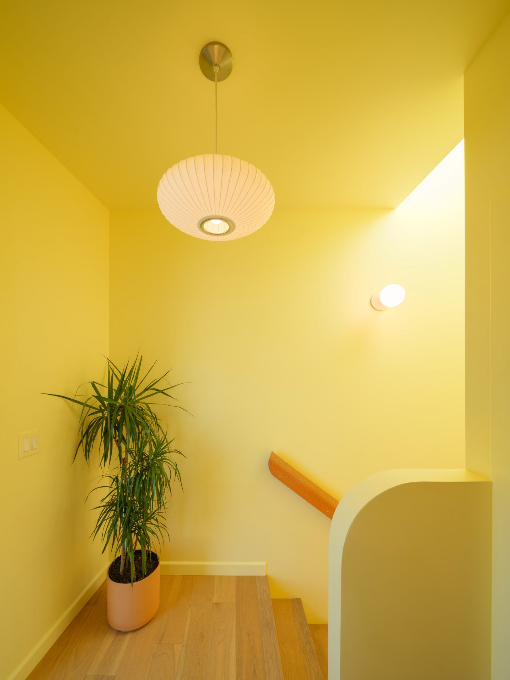 Skylit stairwell painted bright yellow and lined with white oak slats inside the Offset ADU.