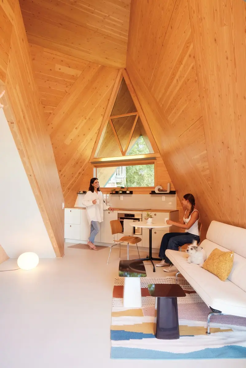 Interior of the Polyhaus ADU showing CLT panel walls, integrated storage, and the mezzanine bedroom above