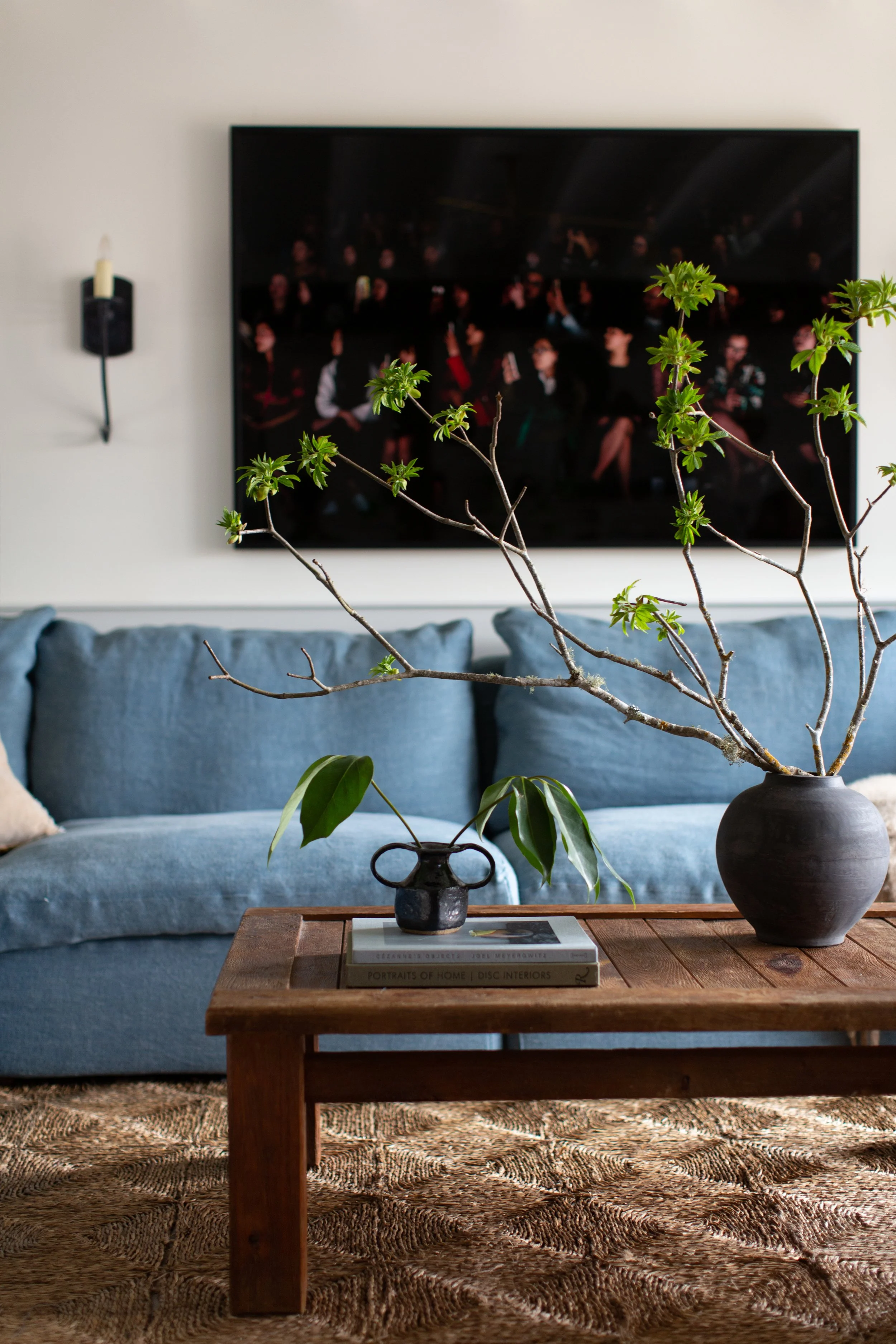 Living space in a converted Outer Sunset garage, with a blue linen sofa, a reclaimed wood table, and art on a white wall