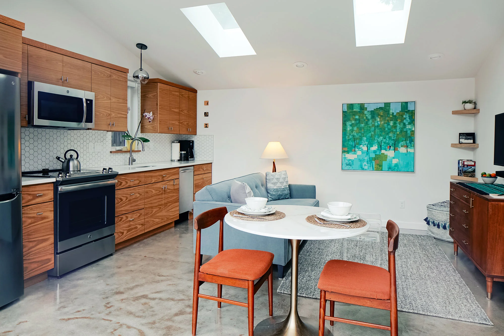 The Wedge ADU great room with three full-height glass doors open to a patio and a polished concrete floor