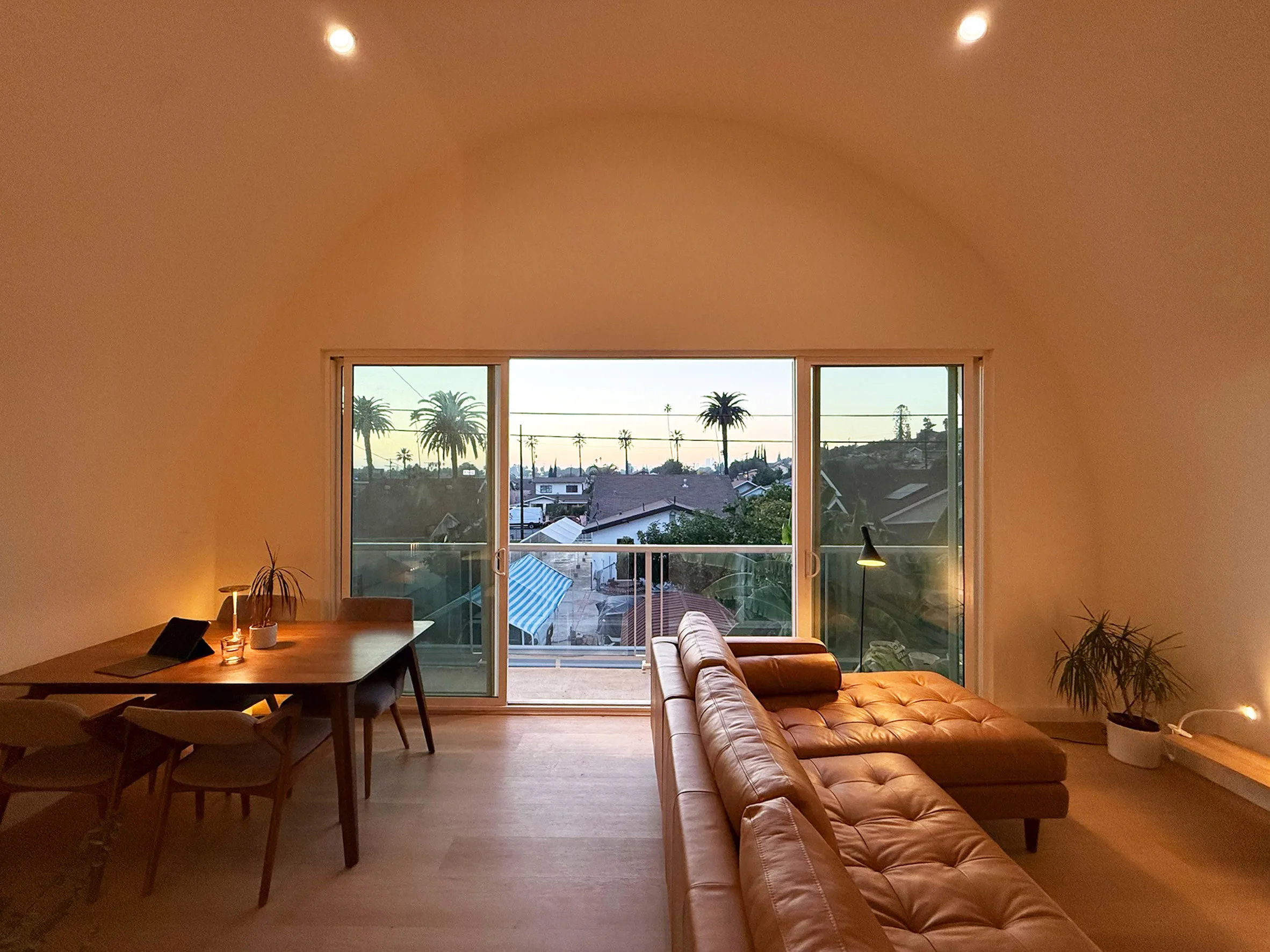 Interior of an arched steel ADU with wood floors, a compact kitchen, and a curved ceiling